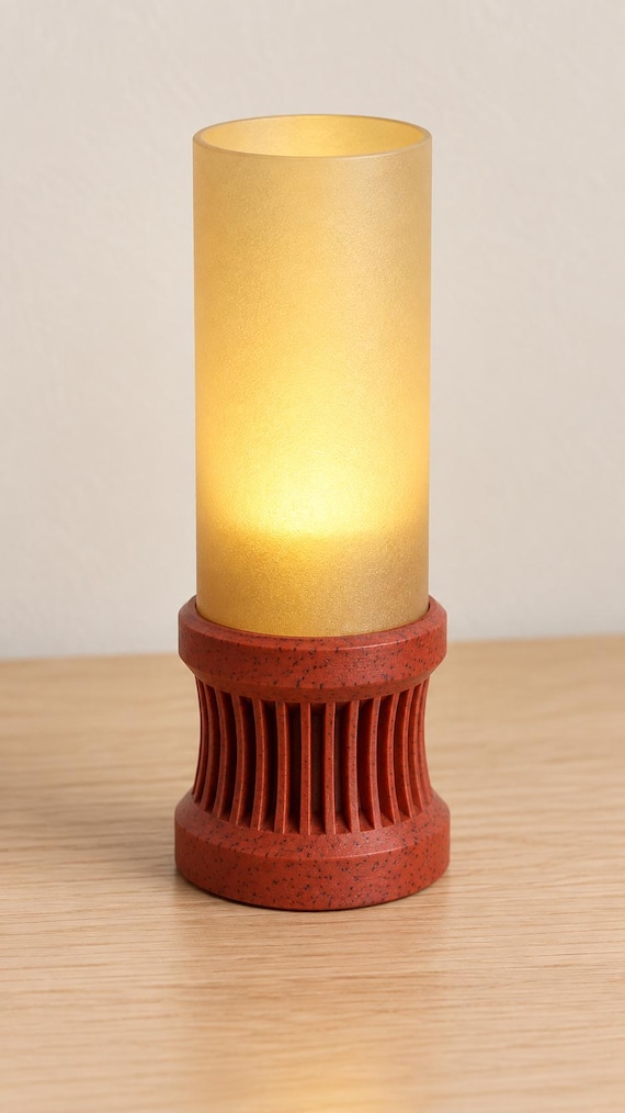 Elevated view of the Granite Amber Alvara lamp showing its Red Granite speckled base, open Mellow Yellow shade and soft tea light glow.