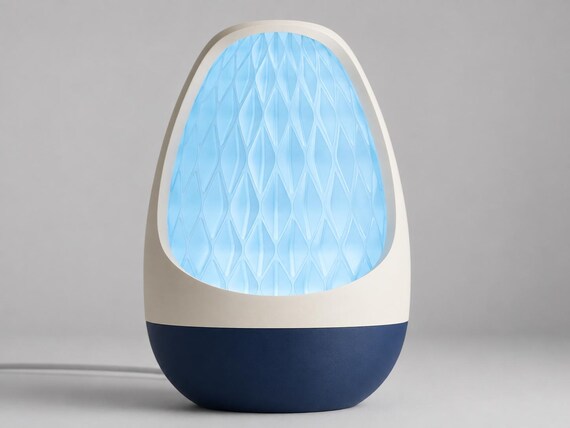 Lumenvale USB lamp in Frost, assembled with a Bone White frame, Dark Blue base and glowing Ice Blue patterned shade on pale gray.