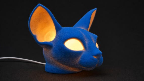 Cobalt Blue VelvetGaze Sphynx cat lamp glowing in a close side view