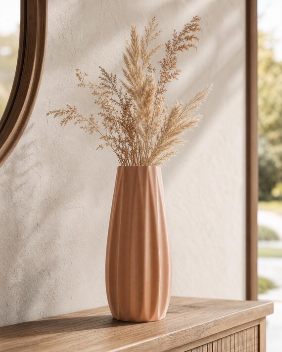 Close-up of a Terracotta Loomrise vase with dried grasses on a wood console