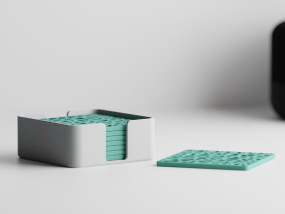 Low-angle close-up of eight CanopyLace square coasters stacked in the storage holder