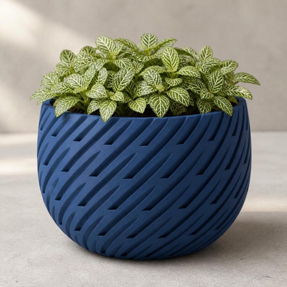 Close-up of the Marine Blue Leafstream sculptural planter with patterned green foliage