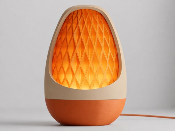 Lumenvale USB lamp in Ember, assembled with a Desert Tan frame, Terracotta base and glowing Orange patterned shade on pale gray.