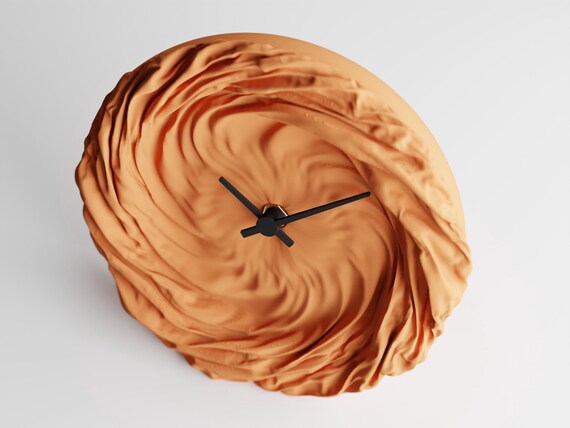 Angled close-up of the FoldWhirl wall clock and sweeping fabric-look folds