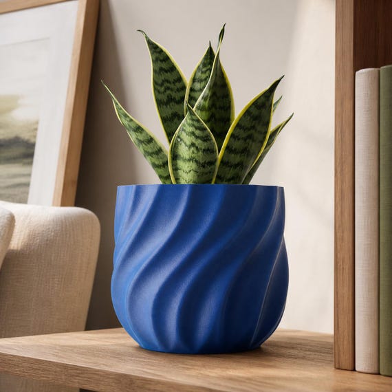 Cobalt Blue CurrentFold plant pot with a compact snake plant on a wood shelf