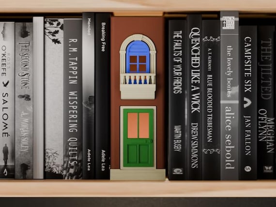 Terracotta townhouse facade with cream trim, green door and blue upper window between books.