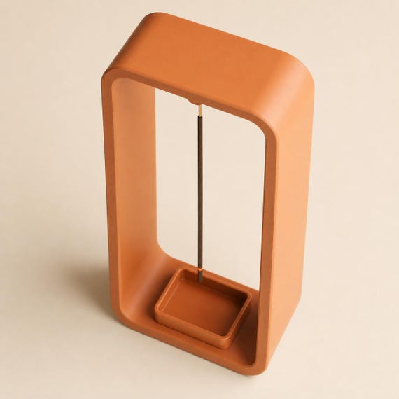 High-angle close-up of a Pumpkin Orange AeroCinder suspended incense stand