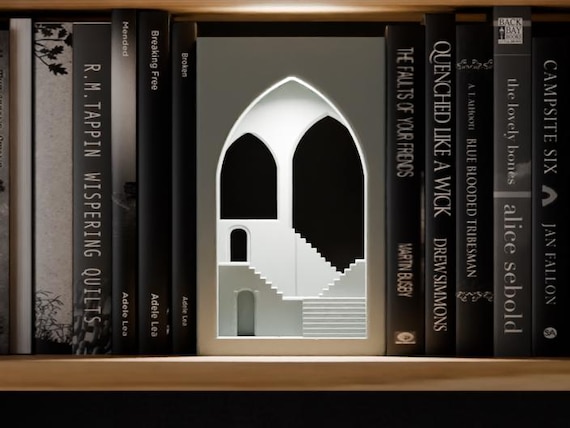 Veilstep Temple Book Nook in a light neutral color, shown from the front between books on a wooden shelf.