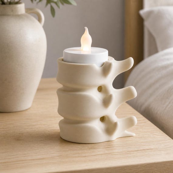Beige compact SpineGlow flameless tealight holder on a minimalist bedside table