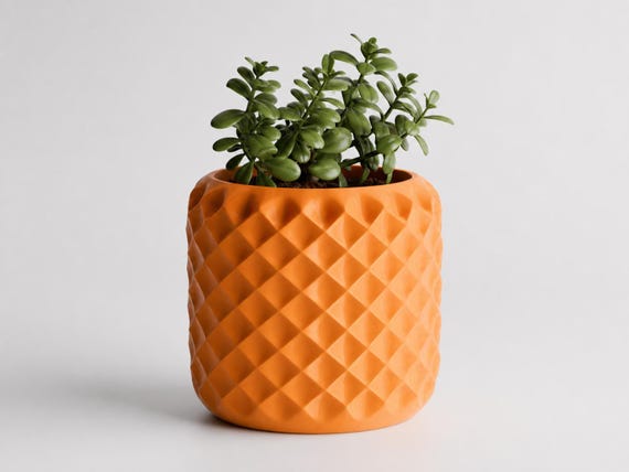 Rear three-quarter detail of a large Pumpkin Orange FacetNest planter with diamond relief