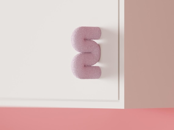 Pale pink wavy cabinet knob on a white cabinet, angled view.