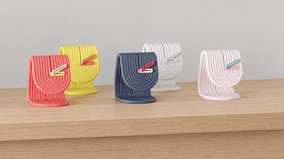 Alternate close-up of Ribbonrise Sculptural Desk Clock examples on light oak, showing their colored faces, hands and body profiles.