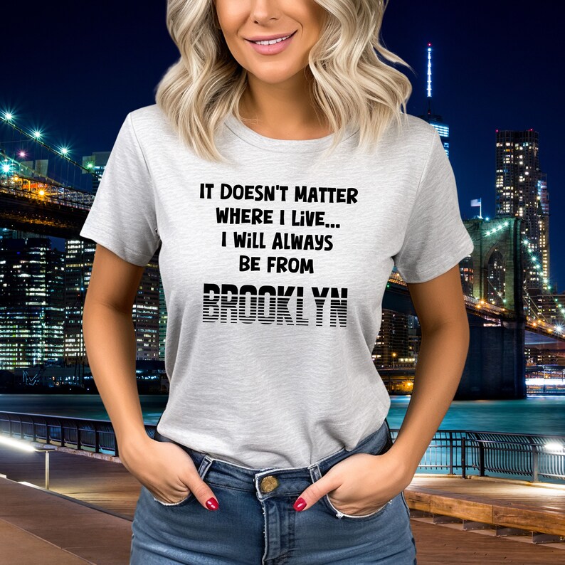 May include: A gray t-shirt with black text that reads "It doesn't matter where I live... I will always be from Brooklyn". The text "Brooklyn" is in a stylized font with black lines.