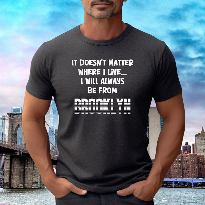 May include: A dark grey t-shirt with white text that reads "It doesn't matter where I live... I will always be from BROOKLYN".