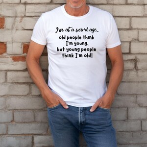 Puede incluir: Camiseta blanca con texto negro que dice "Estoy en una edad extra&ntilde;a... la gente mayor piensa que soy joven. pero la gente joven piensa que soy viejo!"
