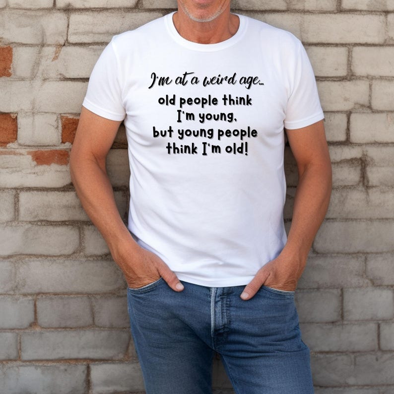 Puede incluir: Camiseta blanca con texto negro que dice "Estoy en una edad extra&ntilde;a... la gente mayor piensa que soy joven. pero la gente joven piensa que soy viejo!"