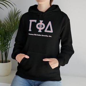 May include: Black hooded sweatshirt with a front pocket and a drawstring hood. The sweatshirt features the Greek letters ΓΦΔ in light blue and pink, with the text "Gamma Phi Delta Sorority, Inc." below.