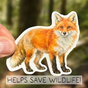May include: A sticker featuring a watercolor illustration of a fox with orange and white fur, and black paws. The sticker has the text "HELPS SAVE WILDLIFE!" at the bottom, with a blurred forest background.