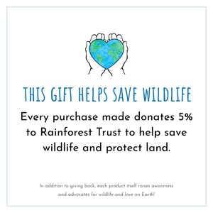 May include: A white background with the text "THIS GIFT HELPS SAVE WILDLIFE." The image includes a drawing of two hands cupping a heart-shaped globe. The text states that every purchase donates 5% to the Rainforest Trust.