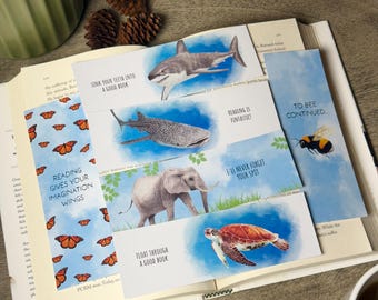 May include: A collection of colorful bookmarks featuring illustrations of a shark, whale shark, elephant, sea turtle, and bee. Each bookmark has a unique quote about reading, such as "Sink your teeth into a good book."