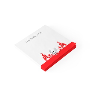Pu&ograve; includere: Un blocco note bianco con un bordo rosso. Il blocco note ha un'illustrazione in bianco e nero di una scrivania in fiamme con il testo "Sto bene. Tutto &egrave; BENE."