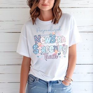 May include: White t-shirt with a blue and pink plaid design that says "Personalized Newborn Screening Team" with illustrations of babies.