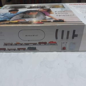 May include: A white box with a train set on the front. The box has a picture of two children playing with the train set. The text on the box says "Papa, komm spielen!" and "202 x 122 cm / 80' x 37".