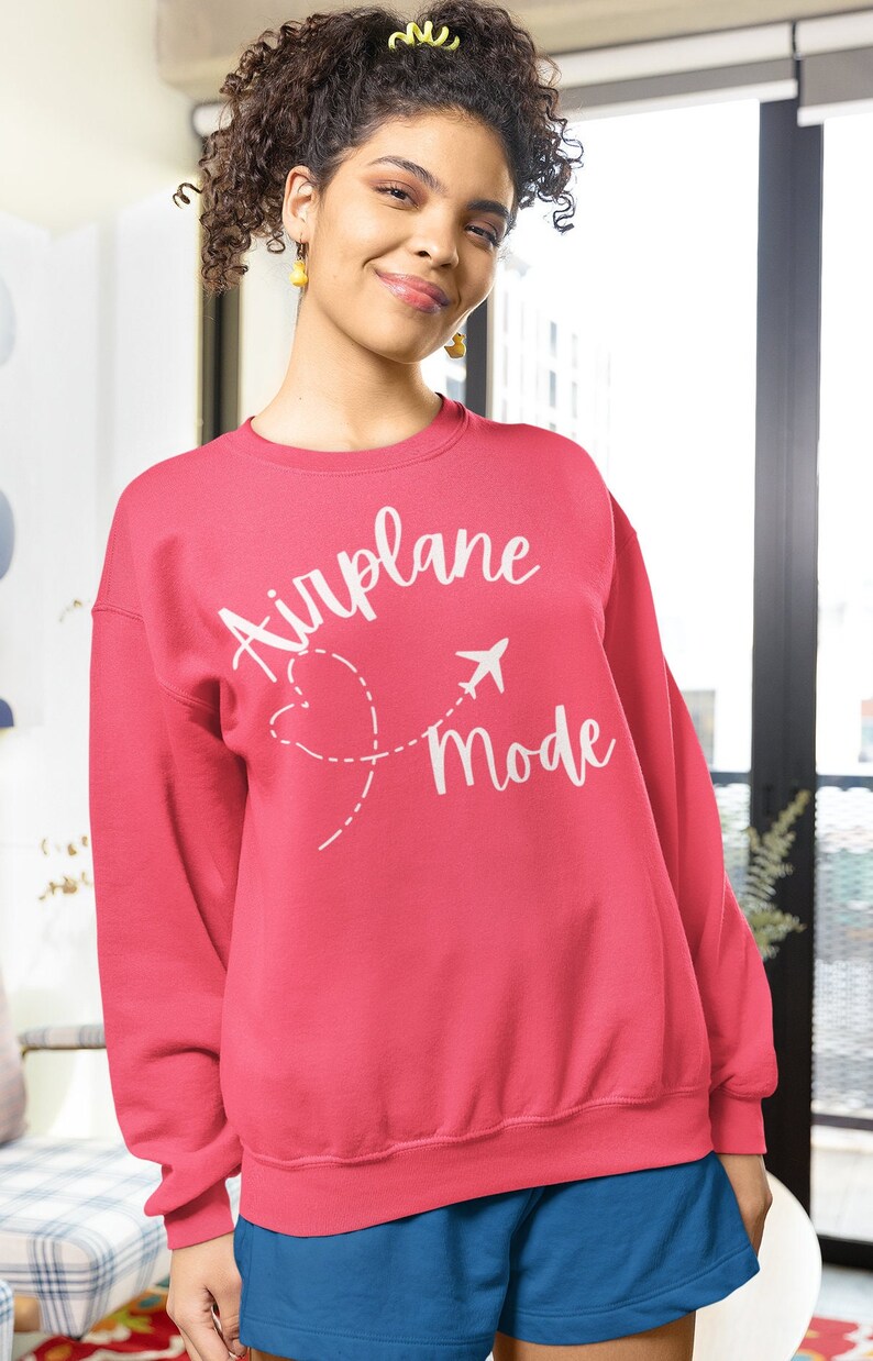 May include: A pink sweatshirt with the text "Airplane Mode" in white lettering. The text is accompanied by a stylised airplane and a heart with a dashed line.