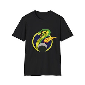 May include: Black t-shirt featuring a colorful graphic of a green and yellow cobra inside a yellow and blue circle, with a red star and a crescent moon. The design is centered on the front of the shirt.