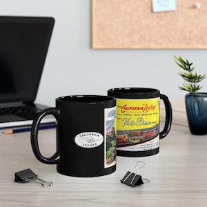 May include: Two black ceramic mugs with a vintage travel poster design. The mug on the left has the text "California Zephyr" in a white oval. The mug on the right has the text "The California Zephyr" in red and "Vista-Dome Cars" in yellow.