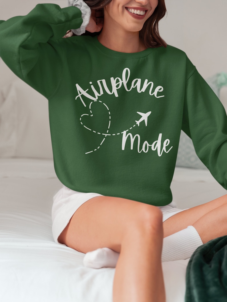 May include: A green sweatshirt with the text "Airplane Mode" in white lettering. A white airplane icon and a heart with a dashed line are next to the text.