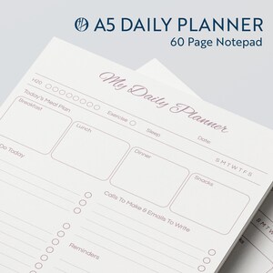 May include: A white daily planner notepad with a pink title "My Daily Planner" and sections for "Today's Meal Plan", "Exercise", "Sleep", "Do Today", "Calls To Make & Emails To Write", and "Reminders".