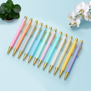 May include: A set of 12 pastel coloured ballpoint pens with gold accents. The pens are arranged in a row from darkest to lightest.