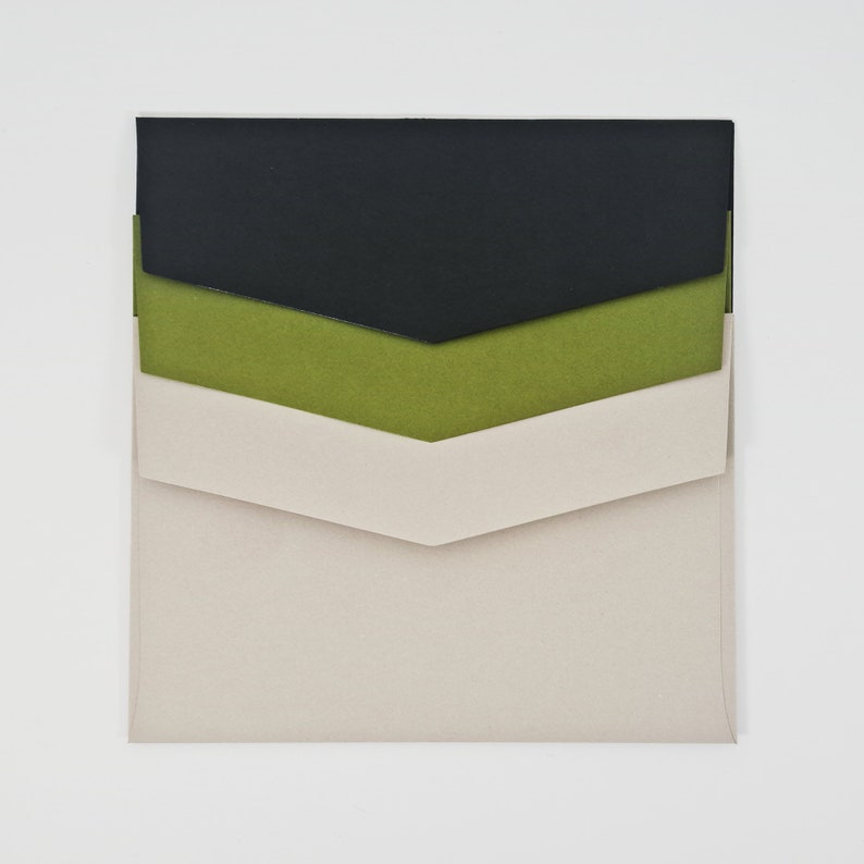 May include: A set of three envelopes in black, green, and beige. The envelopes are nested inside each other, with the black envelope on top and the beige envelope on the bottom.