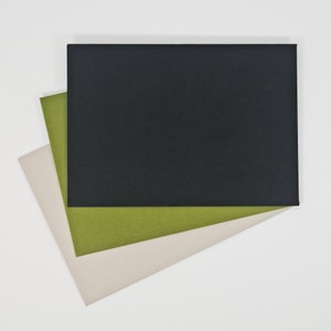 May include: Three sheets of paper stacked on top of each other. The top sheet is black, the middle sheet is green, and the bottom sheet is a light beige color.