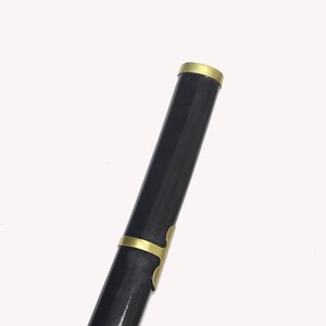 A close-up of the black katana scabbard, showing a gold band at the top and gold accents along its length.