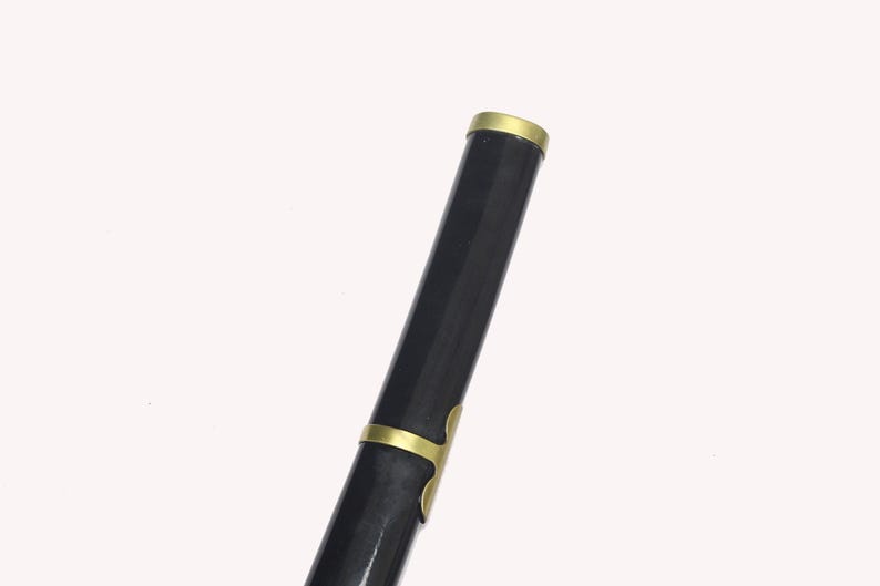 A close-up of the black katana scabbard, showing a gold band at the top and gold accents along its length.