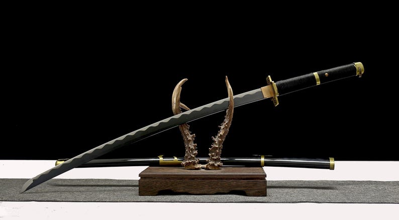 A black and gold katana with a silver blade rests on an antler-like stand, with its matching scabbard visible behind it.