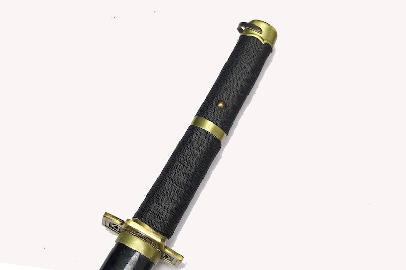 A close-up of the katana's black textured hilt with gold accents and a gold pommel.