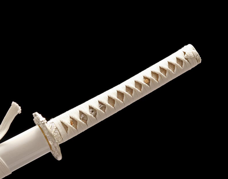 Close-up of a white katana hilt wrapped in white cord with a diamond pattern, showing a silver-colored guard.