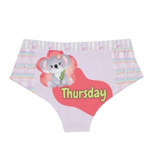 May include: Light purple underwear with a cartoon koala bear illustration. The koala is holding a sprig of leaves and is surrounded by a flower-shaped design. The word "Thursday" is printed in green.