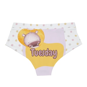 May include: White underwear with a pattern of pink and yellow polka dots. The front features a cartoon hippo inside a yellow heart shape, with the word "Tuesday" in black text below.