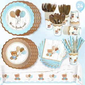 May include: A blue and brown teddy bear themed party supplies set with 24 pieces. The set includes plates, napkins, cups, straws, and a table cover. The plates and napkins feature a teddy bear holding balloons. The cups have a brown and blue striped pattern. The straws are brown and blue striped. The table cover has a blue and brown border with a repeating pattern of teddy bears holding balloons.