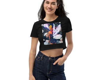 Peut inclure: T-shirt noir à manches courtes et à ourlet court avec un imprimé graphique coloré d'une femme avec des ailes. La femme porte une robe à fleurs et une couronne de fleurs sur la tête.