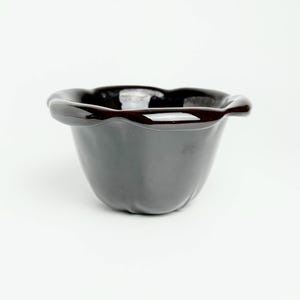 Puede incluir: Una maceta de cerámica negra con un borde festoneado.