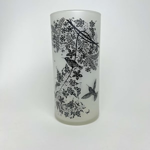 May include: A frosted glass tumbler featuring a black and white design of hummingbirds and flowers. The design is silhouetted against a white background.