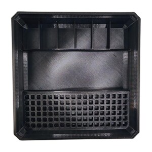 May include: A black, rectangular organiser with multiple compartments. The top section has vertical dividers, the middle is a large open space, and the bottom features a grid of small square holes. The organiser is made of a textured material.