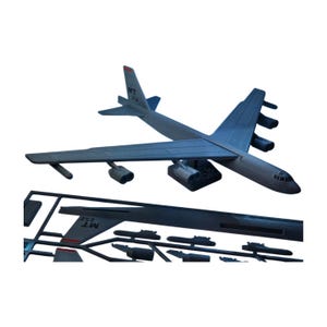 May include: A gray plastic model of a B-52 bomber airplane with a detailed design. The model includes separate parts for assembly, with the text "MT 252" visible on the tail.