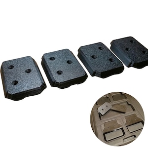 May include: Four dark grey rectangular mounting plates with three holes each. The plates have a textured surface and a beveled edge. A circular inset shows the plates in a tray.