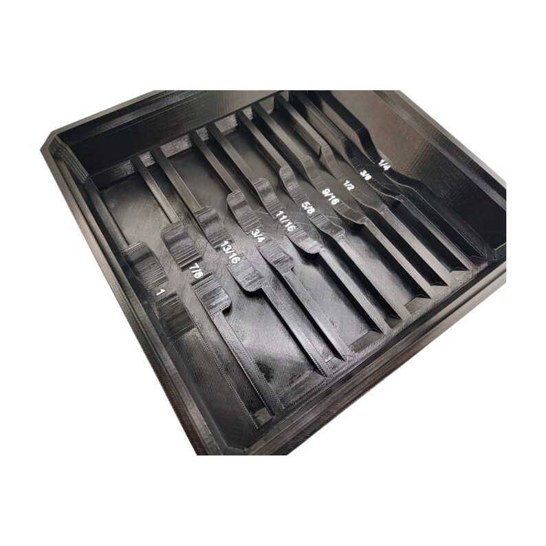 Puede incluir: Un organizador de herramientas negro, impreso en 3D, con m&uacute;ltiples ranuras. El organizador est&aacute; dise&ntilde;ado para guardar varias herramientas, con medidas como 1/4, 3/8, 1/2, 5/8, 9/16, 11/16, 3/4, 13/16, 7/8 y 1 pulgada claramente etiquetadas.